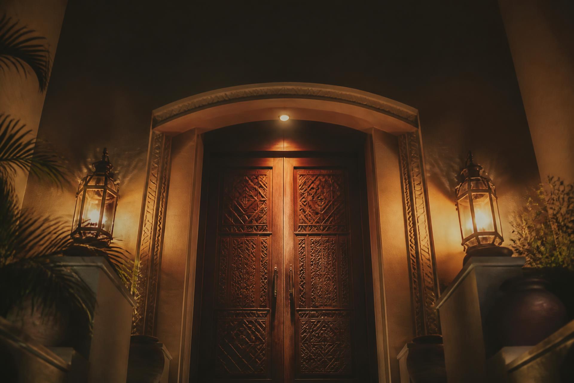 Lantern-lit estate doors at dusk, the entrance to House of Sumayya.